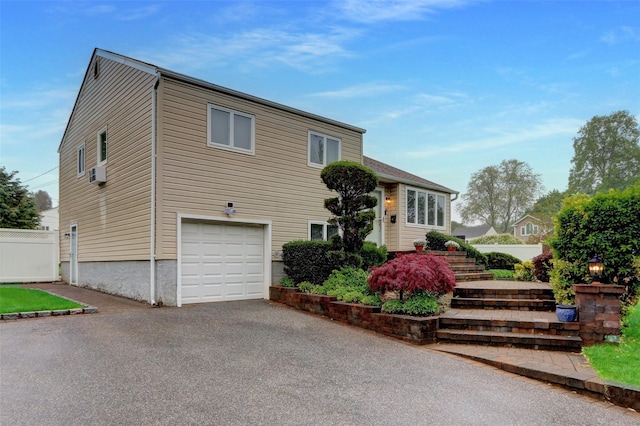 exterior space featuring aphalt driveway, a garage, and fence
