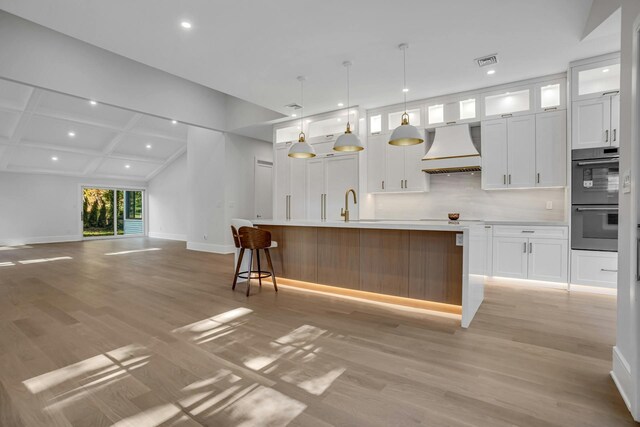 kitchen with custom range hood, double wall oven, light wood-style floors, recessed lighting, and white cabinets