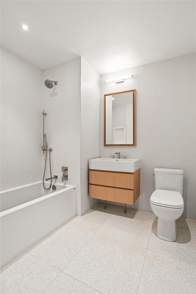 bathroom with vanity, toilet, tile walls, and speckled floor