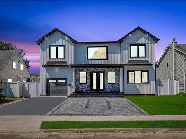 modern farmhouse style home with fence, a garage, stone siding, aphalt driveway, and a front lawn