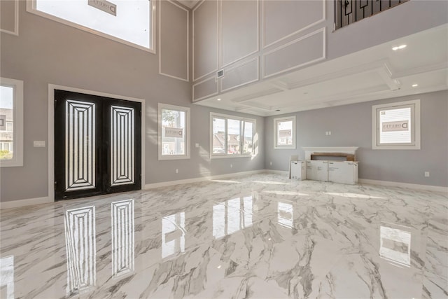 unfurnished living room featuring baseboards, marble finish floor, french doors, and a towering ceiling