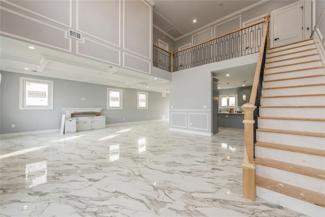 unfurnished living room featuring stairs, marble finish floor, a healthy amount of sunlight, and a decorative wall