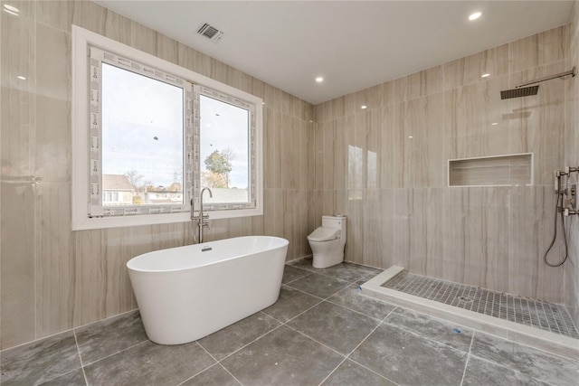 full bath with tiled shower, tile patterned floors, a freestanding bath, visible vents, and tile walls