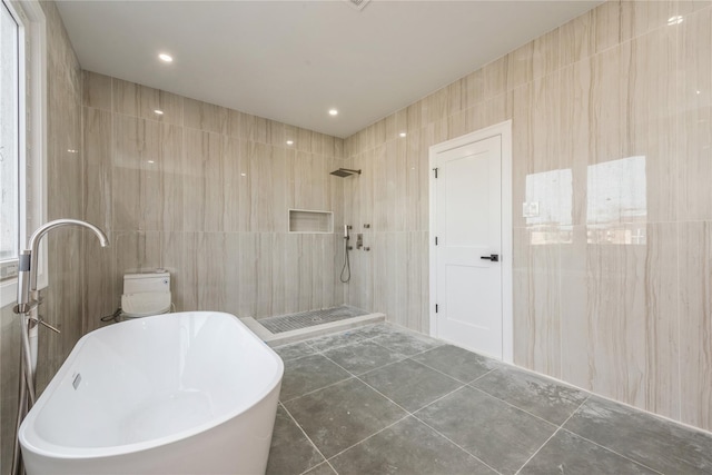 bathroom with a soaking tub, tile walls, tile patterned flooring, and tiled shower