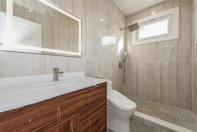 bathroom featuring vanity, toilet, tile walls, and tiled shower