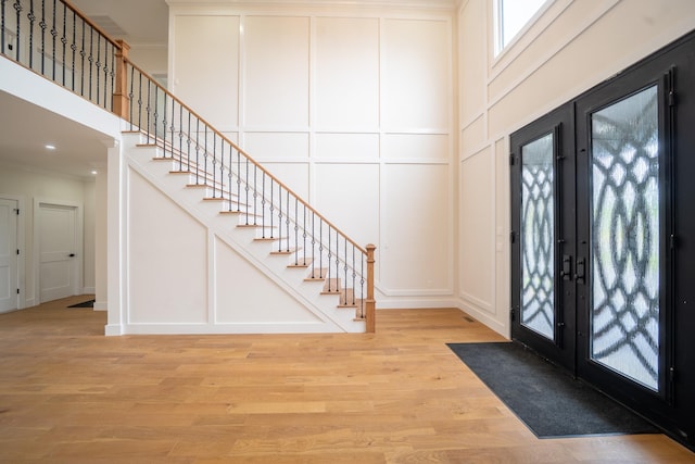 396 Argyle Rd, East Meadow, NY 11554 - entrance foyer with a decorative wall, stairs, crown molding, light wood-style floors, and french doors