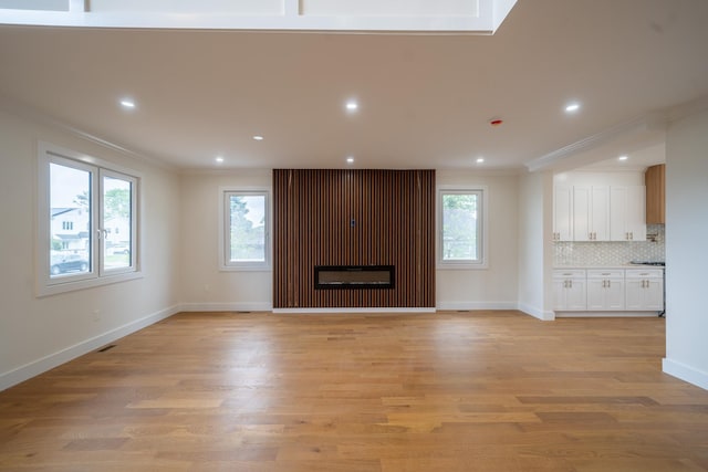 396 Argyle Rd, East Meadow, NY 11554 - unfurnished living room with crown molding, light wood finished floors, baseboards, recessed lighting, and a glass covered fireplace