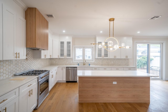 396 Argyle Rd, East Meadow, NY 11554 - kitchen with appliances with stainless steel finishes, healthy amount of natural light, glass insert cabinets, ornamental molding, and recessed lighting
