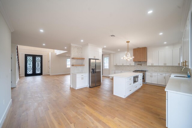 396 Argyle Rd, East Meadow, NY 11554 - kitchen with appliances with stainless steel finishes, a kitchen island, backsplash, a chandelier, and ornamental molding