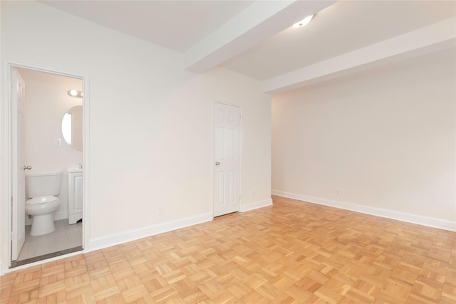spare room featuring baseboards and beamed ceiling