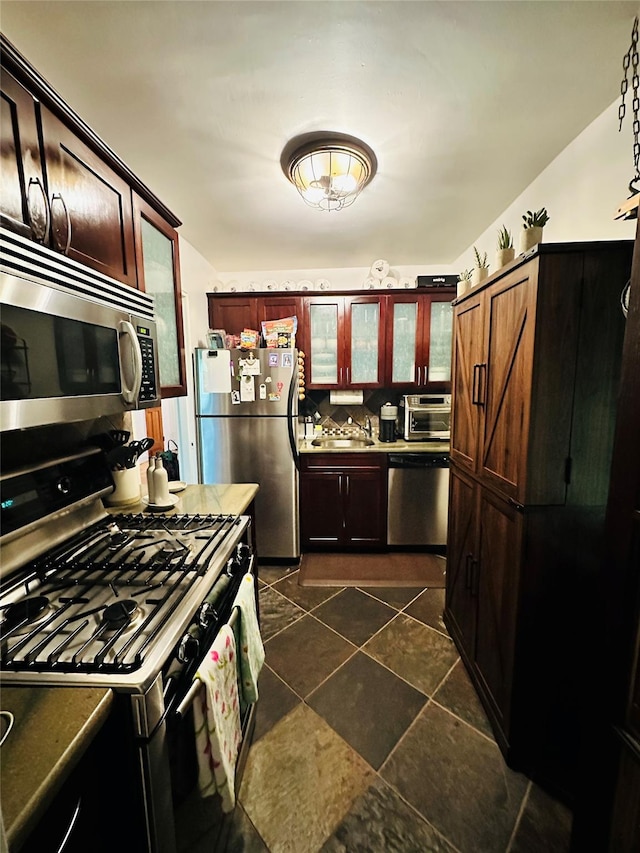 kitchen with a sink, stainless steel appliances, glass insert cabinets, and a toaster