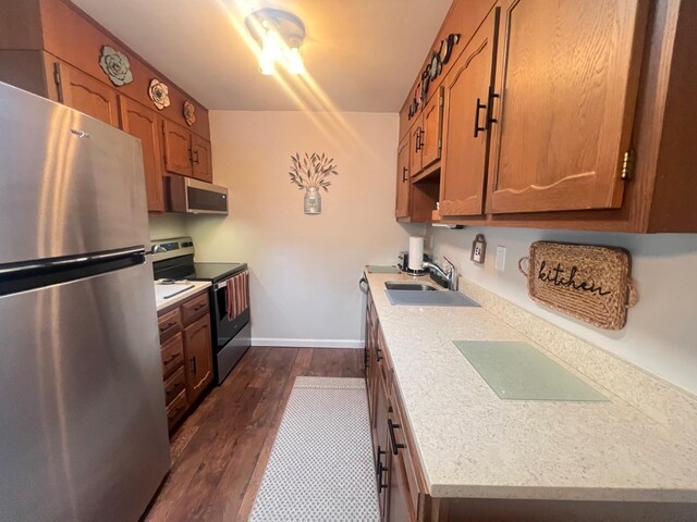232A Blackpool Ct Unit 232A, Ridge, NY 11961 - kitchen featuring appliances with stainless steel finishes, a sink, light countertops, dark wood-type flooring, and baseboards