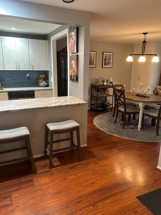 118 Skyline Dr, Coram, NY 11727 - kitchen with dishwasher, backsplash, dark wood-style flooring, a breakfast bar area, and light stone countertops