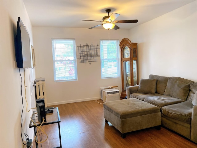 living area with baseboards, wood finished floors, a ceiling fan, and a healthy amount of sunlight