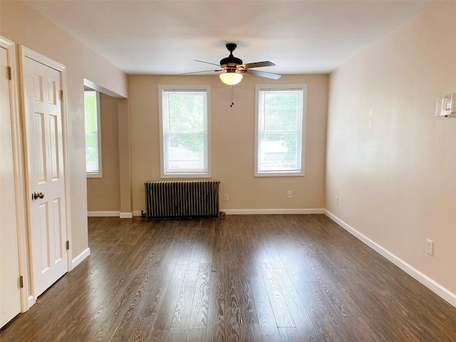 empty room featuring radiator, baseboards, a ceiling fan, and dark wood finished floors