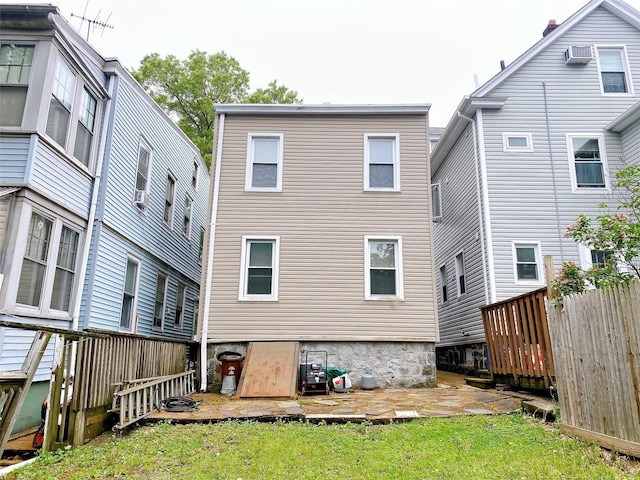 rear view of property with a yard, a patio, a wall mounted AC, and fence
