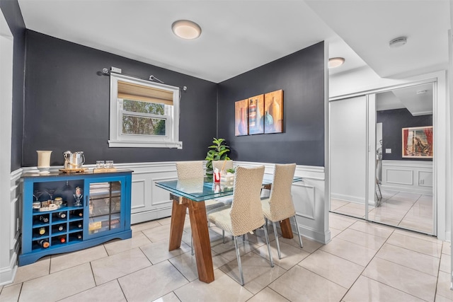 dining area with wainscoting, light tile patterned flooring, and a decorative wall