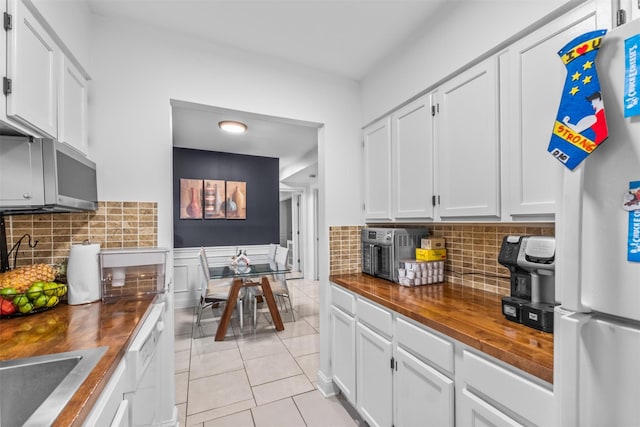 kitchen featuring freestanding refrigerator, butcher block counters, white cabinetry, and light tile patterned floors