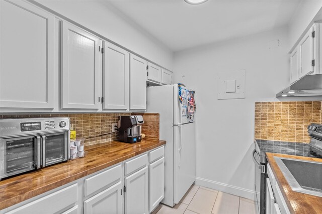 kitchen with electric range, wood counters, under cabinet range hood, freestanding refrigerator, and light tile patterned floors
