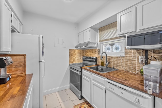 kitchen with appliances with stainless steel finishes, wooden counters, a sink, light tile patterned flooring, and white cabinets