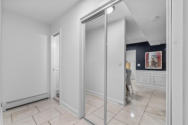 bathroom with a baseboard radiator, tile patterned flooring, wainscoting, and a decorative wall