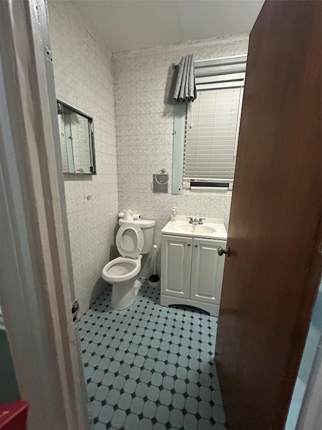 bathroom with tile walls, toilet, tile patterned floors, vanity, and backsplash