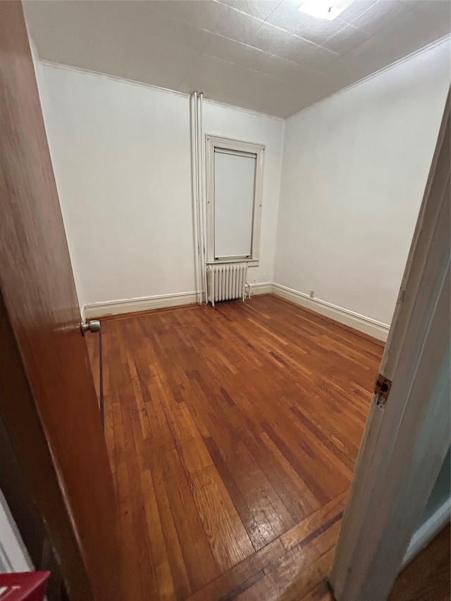 spare room featuring radiator, hardwood / wood-style flooring, and baseboards