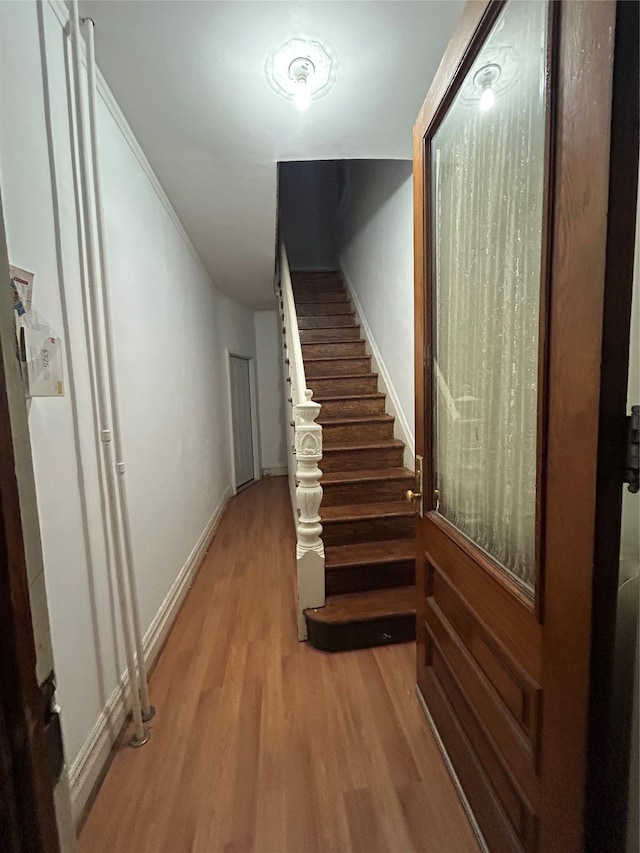 hall with light wood-style flooring, stairs, and baseboards