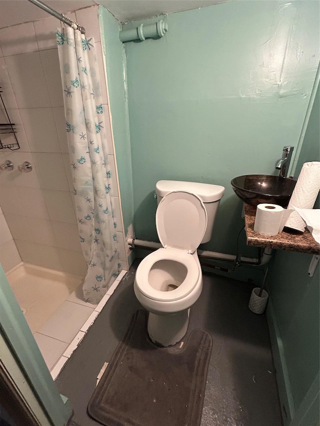 full bath with a tile shower, toilet, and a sink