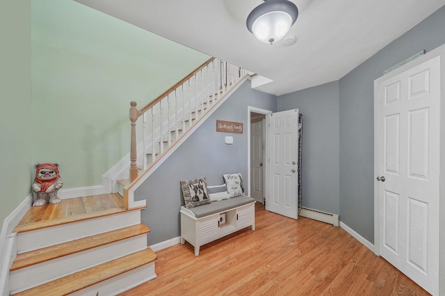stairway featuring baseboard heating, wood finished floors, and baseboards