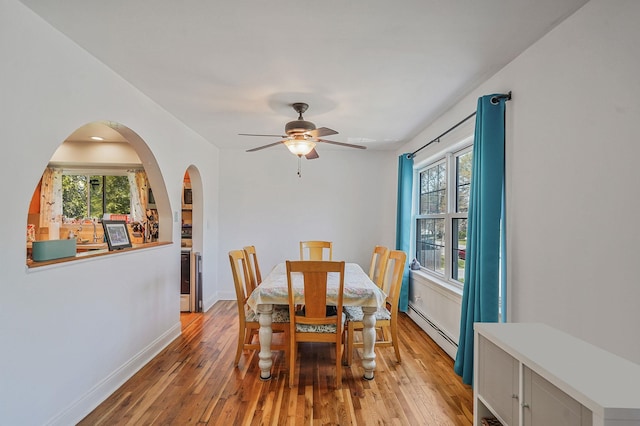 dining space featuring baseboard heating, light wood-type flooring, healthy amount of natural light, and ceiling fan