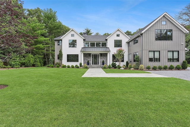 back of house featuring a standing seam roof, board and batten siding, a lawn, metal roof, and stone siding