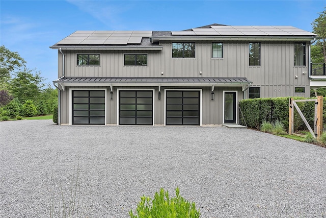 view of front of house featuring a standing seam roof, roof mounted solar panels, driveway, and metal roof