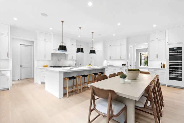 dining space featuring light wood-style flooring, recessed lighting, and wine cooler