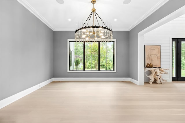 empty room featuring a chandelier, wood finished floors, baseboards, and crown molding