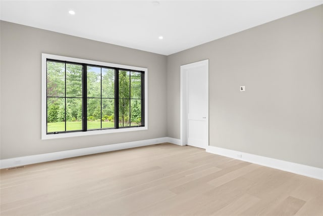 empty room with light wood-style flooring, baseboards, and recessed lighting