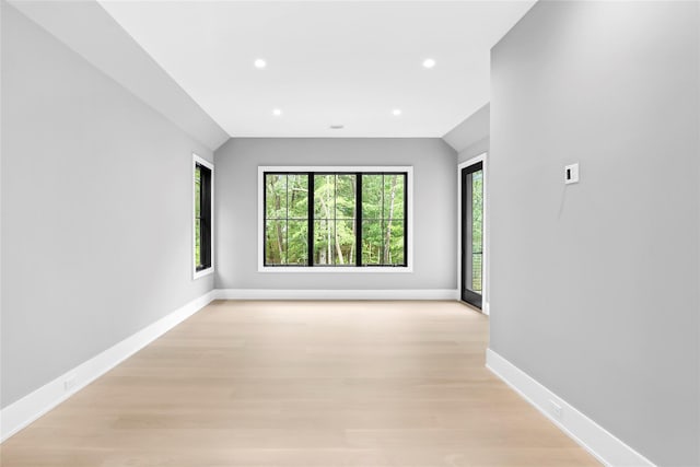 spare room featuring recessed lighting, baseboards, light wood-style flooring, and vaulted ceiling
