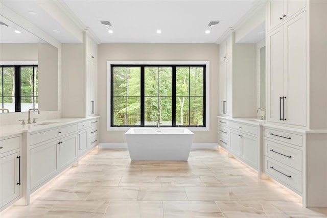 bathroom with baseboards, a freestanding bath, two vanities, and recessed lighting