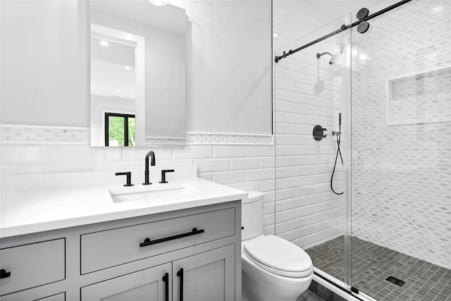 full bathroom with tile walls, toilet, vanity, a shower stall, and a wainscoted wall