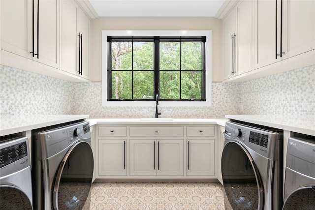 clothes washing area featuring washing machine and dryer, cabinet space, and light tile patterned floors