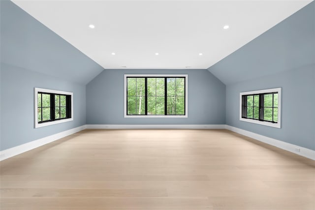 additional living space with plenty of natural light, lofted ceiling, baseboards, light wood-style flooring, and recessed lighting