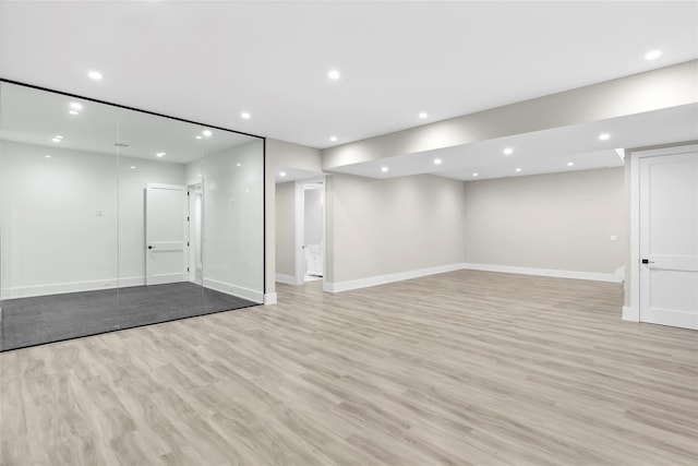 below grade area featuring baseboards, light wood finished floors, and recessed lighting