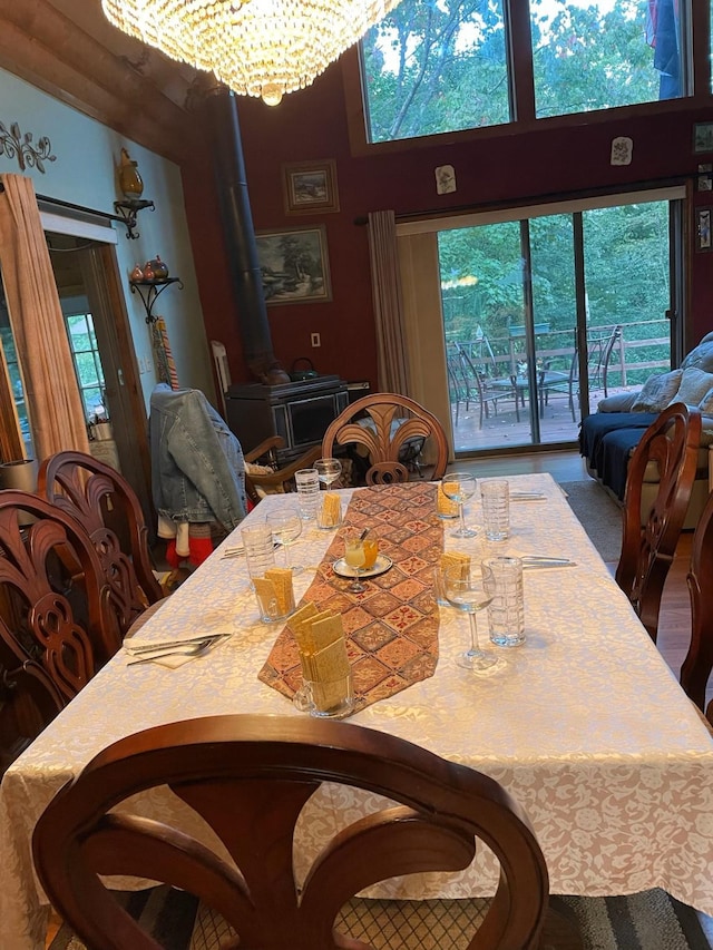 dining area featuring a chandelier, a wood stove, and a high ceiling