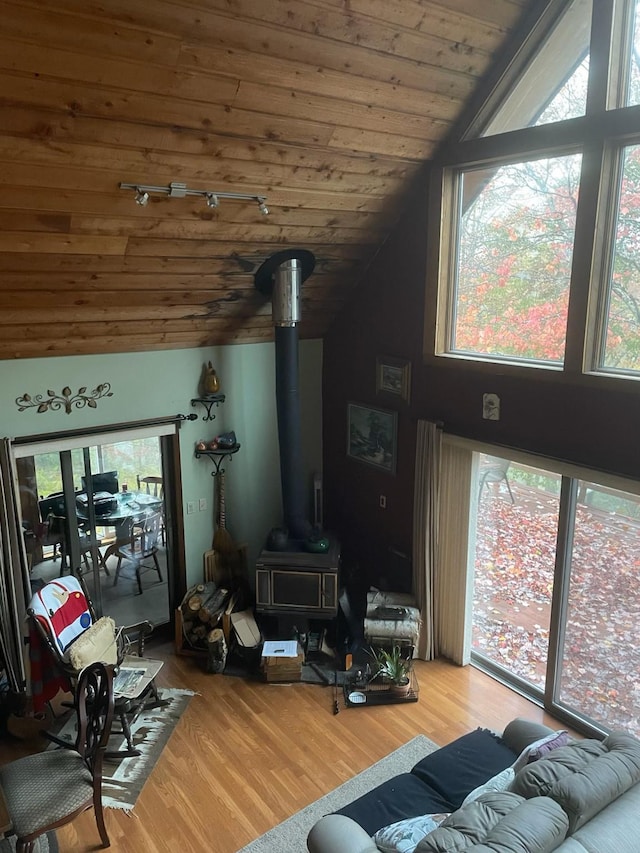living room with lofted ceiling, a wood stove, healthy amount of natural light, wood finished floors, and wood ceiling