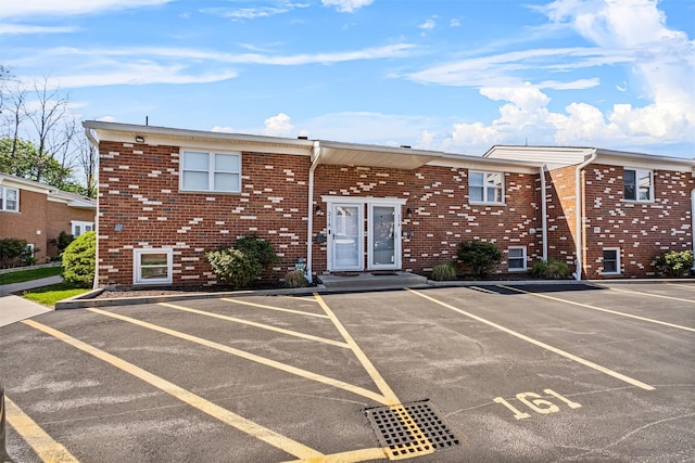view of front facade featuring uncovered parking and brick siding
