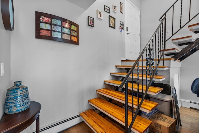 stairs with wood finished floors and baseboard heating