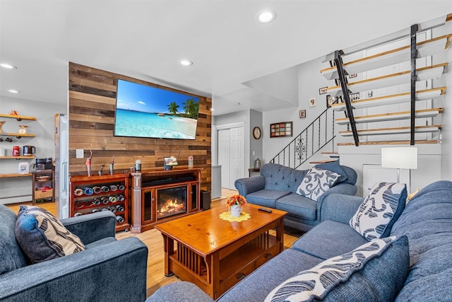 living room with wood walls, recessed lighting, stairs, wood finished floors, and a baseboard heating unit