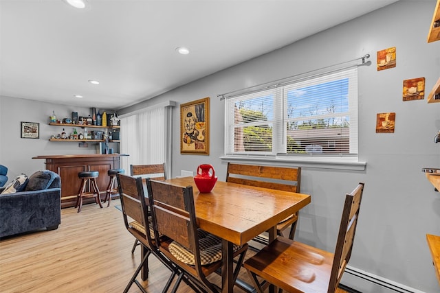 dining room featuring a bar, light wood-type flooring, recessed lighting, and a baseboard radiator