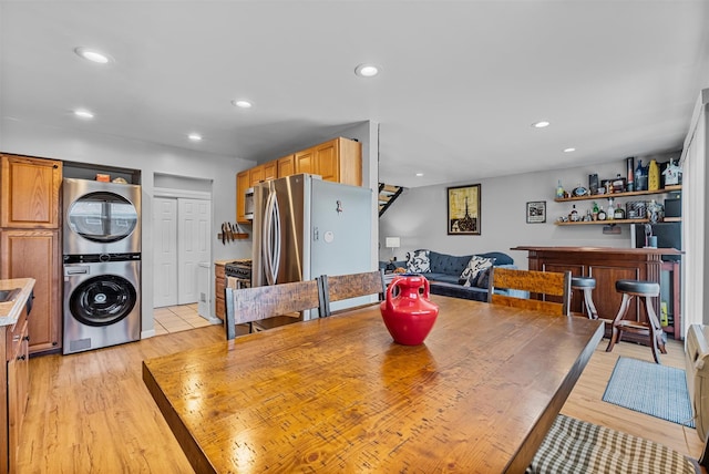 dining space featuring stacked washer / dryer, light wood-style flooring, recessed lighting, and a dry bar