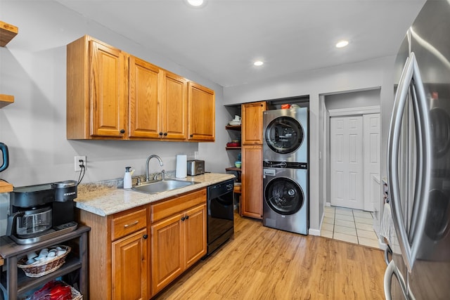 kitchen with freestanding refrigerator, dishwasher, stacked washer / drying machine, a sink, and brown cabinetry